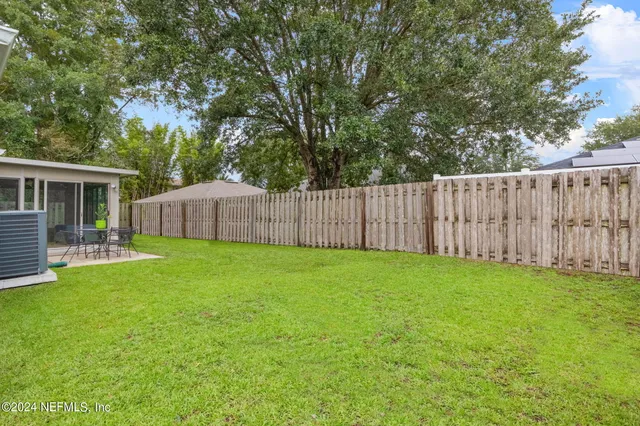 a view of a backyard with table and chairs and wooden fence