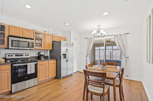 a kitchen that has a table chairs stainless steel appliances and wooden floor