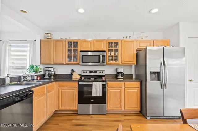 a kitchen with stainless steel appliances granite countertop a refrigerator a stove and a sink