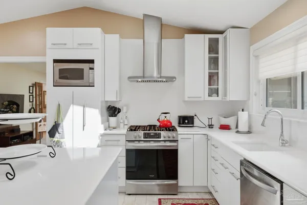 a view of a kitchen with kitchen island a stove a sink dishwasher a dining table and chairs with wooden floor