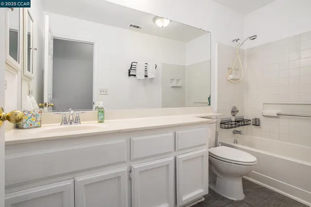 a bathroom with a granite countertop sink a toilet and a bathtub