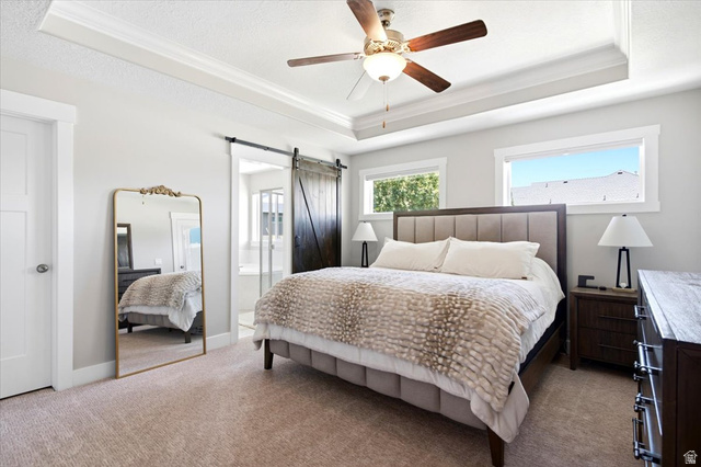 2973 West Red Sand Rd Haven Ogden, UT 84401 - Photo 28 of 30 Spacious bedroom featuring a tray ceiling with a ceiling fan, two windows, and light-colored carpeting