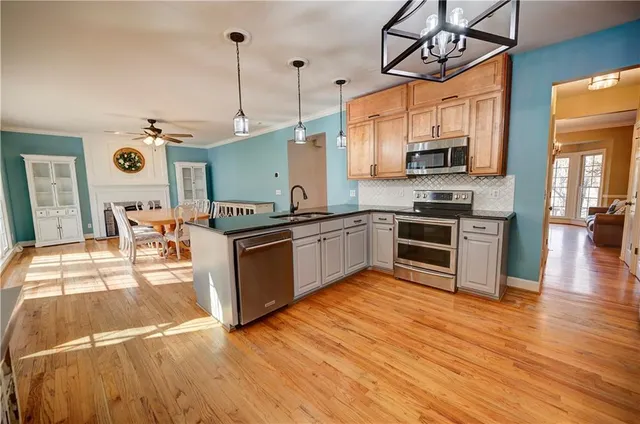 a dining room with wooden floor a chandelier a wooden table and chairs