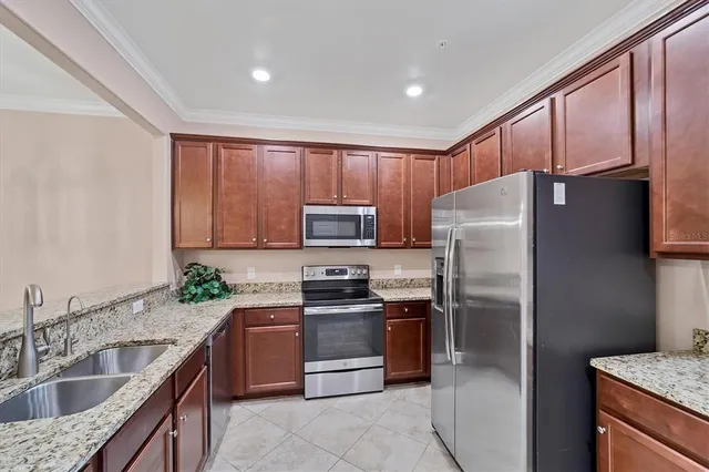 a kitchen with granite countertop stainless steel appliances a refrigerator sink and microwave
