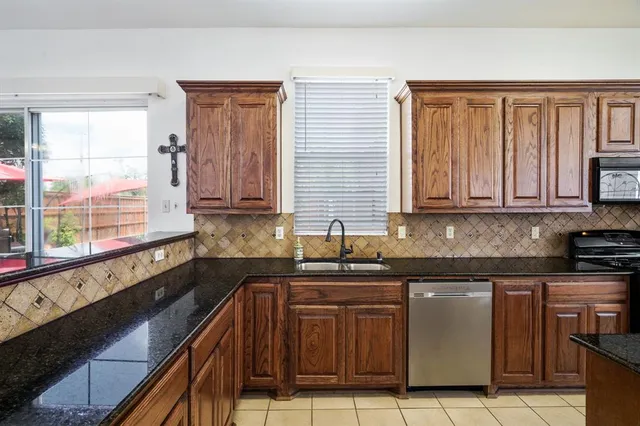a kitchen with granite countertop a sink a stove and cabinets