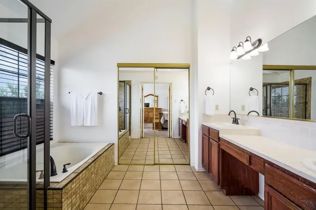 a bathroom with a tub a double vanity sink a mirror and a shower