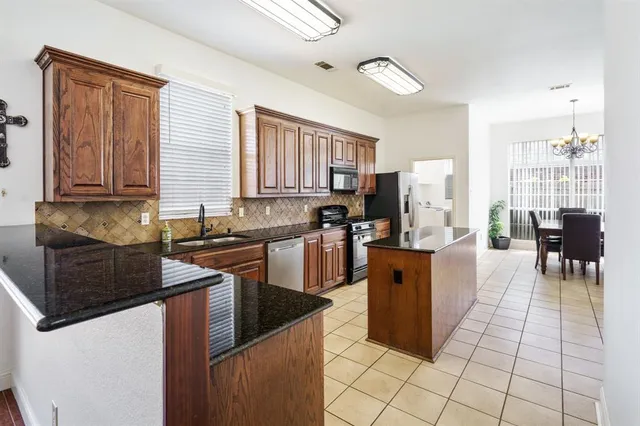 a kitchen with stainless steel appliances granite countertop a stove a sink a microwave and a refrigerator