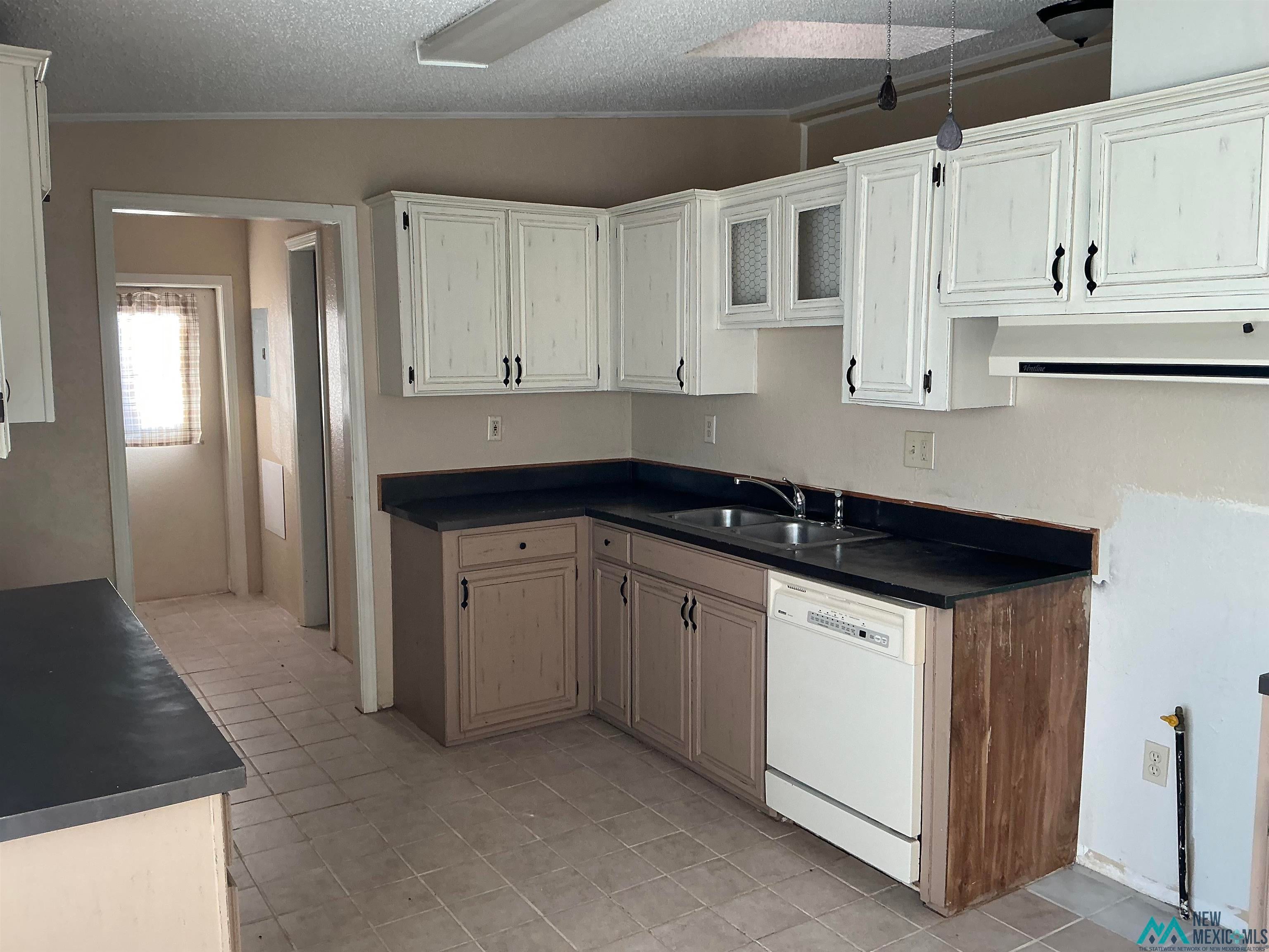 1020 South Fork Road Clovis, NM 88101 - Photo 15 of 37 Kitchen with dark countertops, dishwasher, a textured ceiling, exhaust hood, and light tile patterned flooring