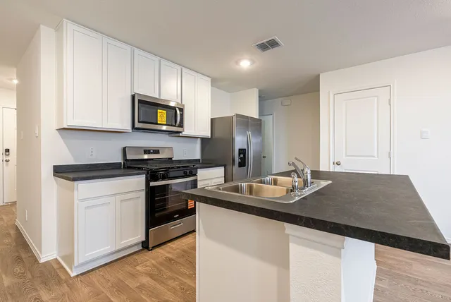 a kitchen with stainless steel appliances granite countertop a refrigerator and a stove top oven