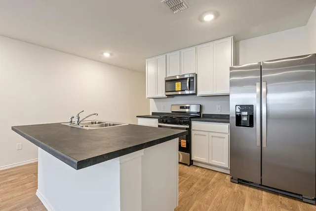 a kitchen with kitchen island a sink stove and microwave