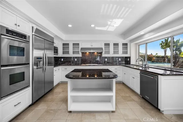 a kitchen with stainless steel appliances granite countertop a stove a sink and a refrigerator