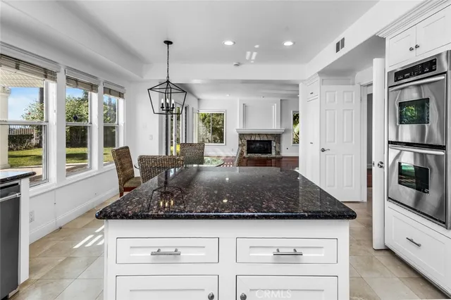 a kitchen with kitchen island granite countertop a stove a sink a oven and a dining table with wooden floor