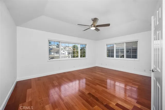 a view of empty room with wooden floor and fan
