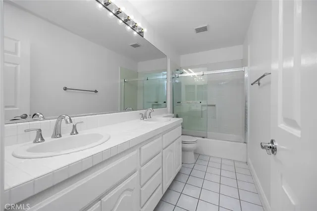 a spacious bathroom with a double vanity sink toilet mirror and shower