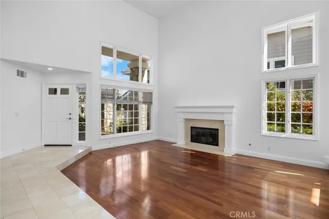 a view of an empty room with wooden floor fireplace and windows