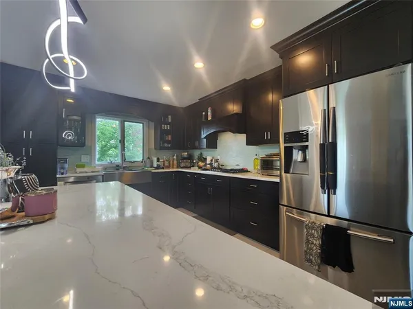 a large kitchen with stainless steel appliances kitchen island granite countertop a refrigerator a sink and a stove
