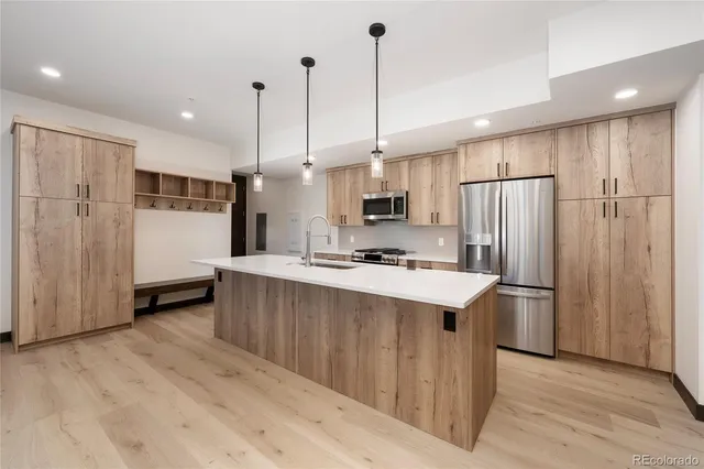 a kitchen with kitchen island stainless steel appliances a refrigerator a sink and wooden floor