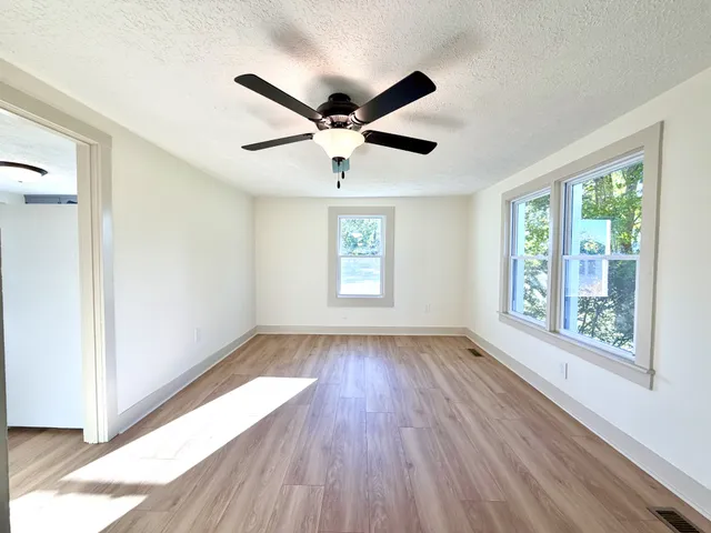 a view of an empty room with wooden floor and a window