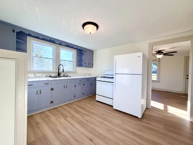 a kitchen with a refrigerator a sink and dishwasher with wooden floor