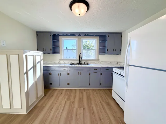 a kitchen with a sink a refrigerator a window and cabinets