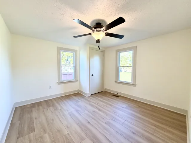 a view of an empty room with wooden floor and a window