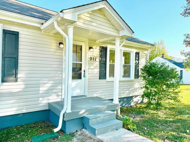 a view of a white house with a small window and potted plants