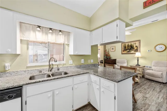 a kitchen with granite countertop stainless steel appliances a sink window and cabinets