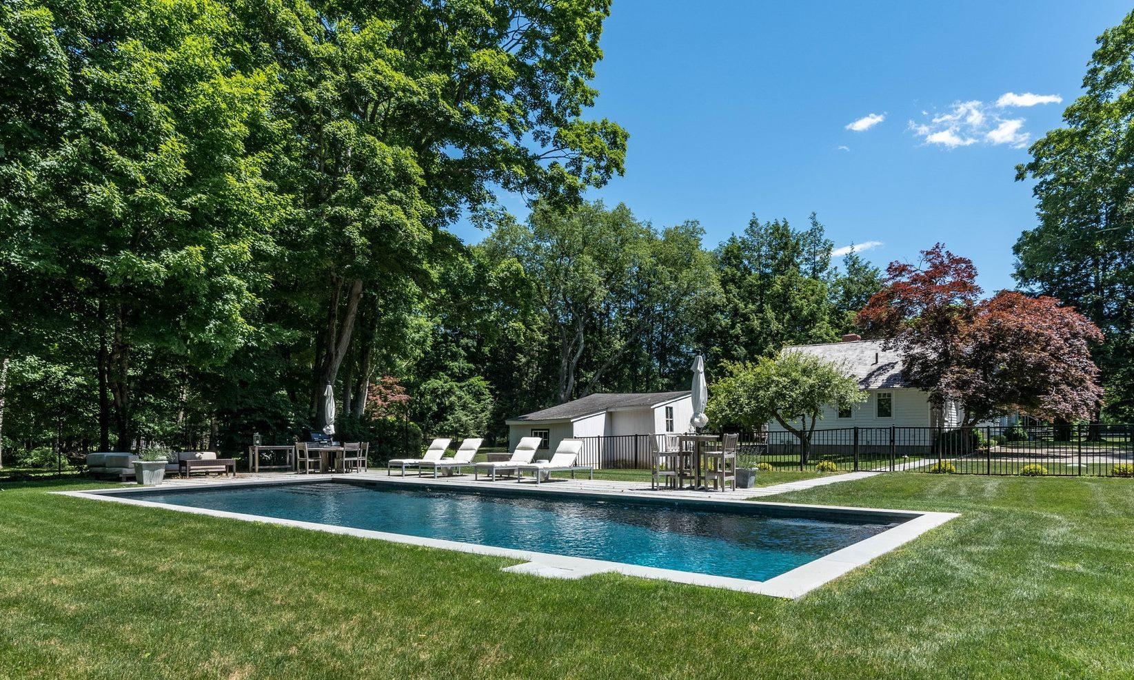 947 Valley Road New Canaan, CT 06840 - Photo 1 of 32 a view of a swimming pool with a bench and trees around