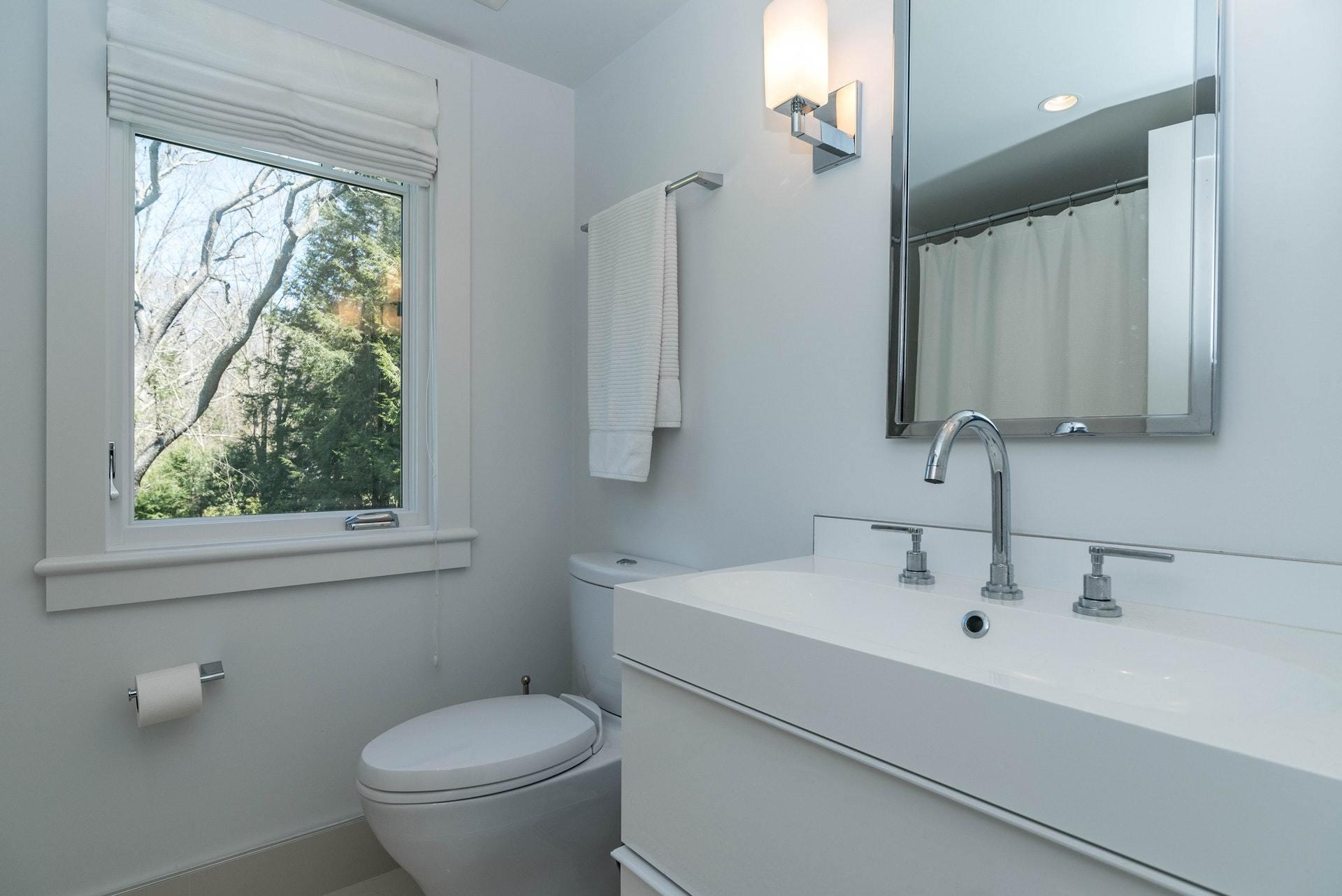 947 Valley Road New Canaan, CT 06840 - Photo 25 of 32 a bathroom with a toilet a sink a mirror and a window