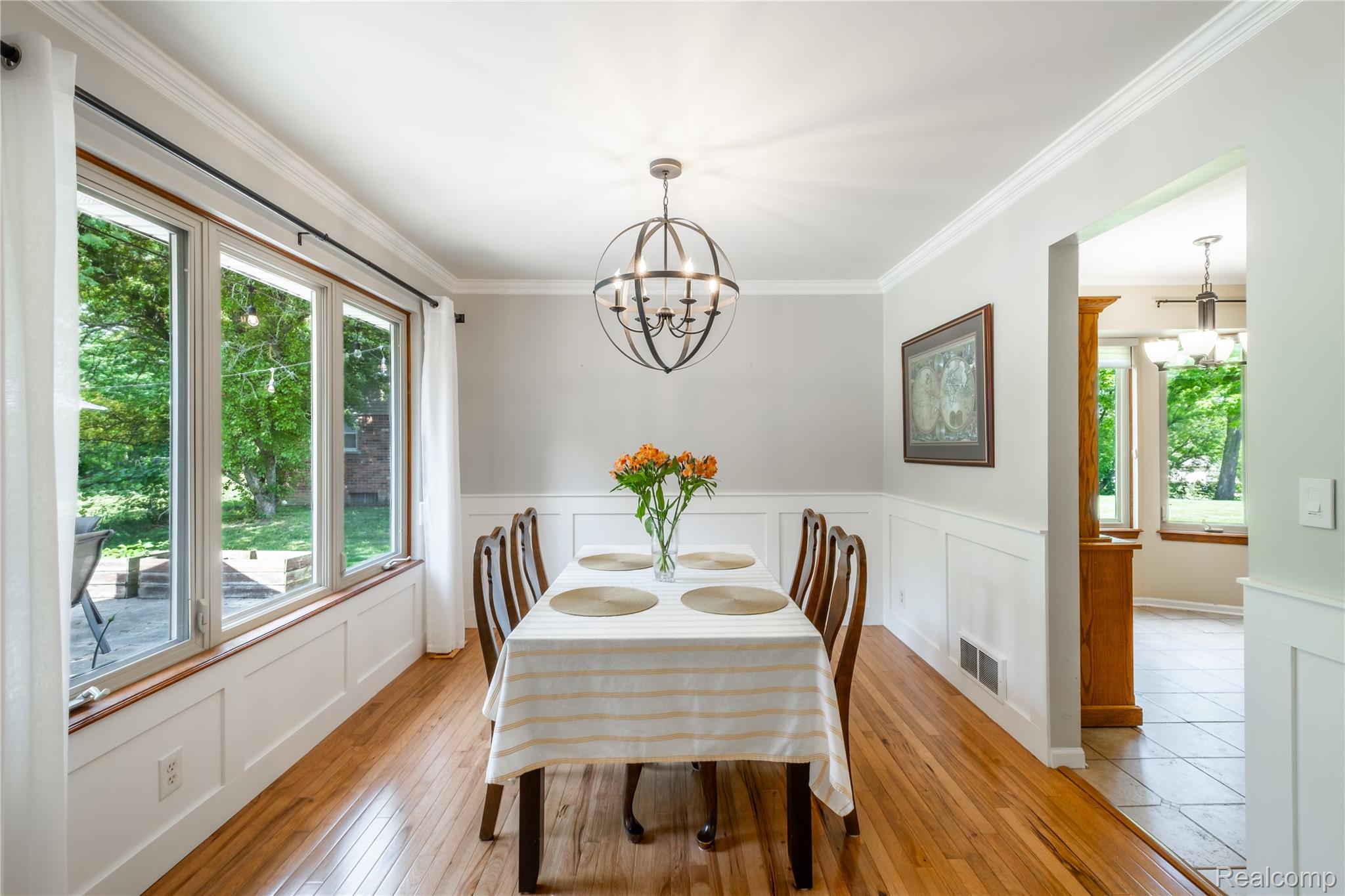 3483 Lahring Road Linden, MI 48451 - Photo 17 of 34 Formal dining space featuring a multi-pane window, hardwood flooring, wainscoting, crown molding, and an industrial-style chandelier