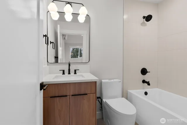 a bathroom with a sink a toilet a mirror a vanity and shower
