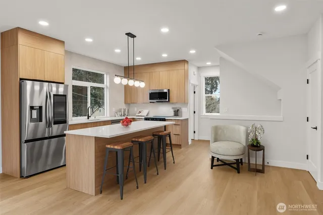 a kitchen with stainless steel appliances kitchen island granite countertop a sink and a refrigerator