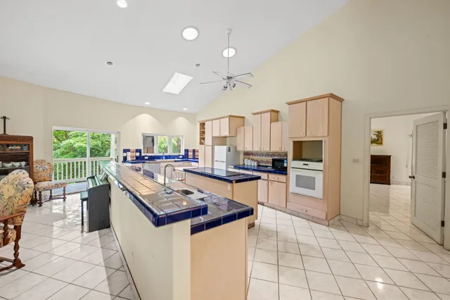 a kitchen with stainless steel appliances kitchen island granite countertop a refrigerator a stove top oven and a sink with granite countertops