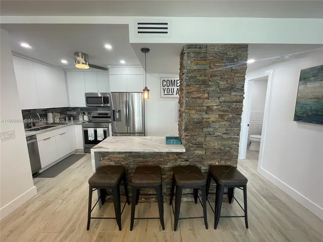 a kitchen with stainless steel appliances a dining table chairs stove and refrigerator