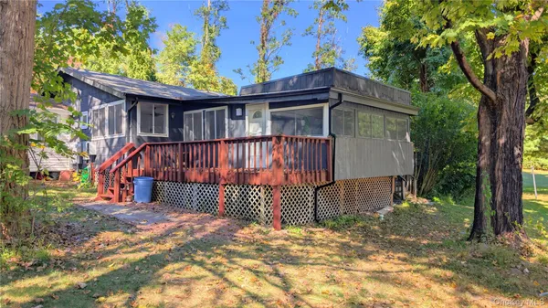 a view of a small house with wooden fence and large trees