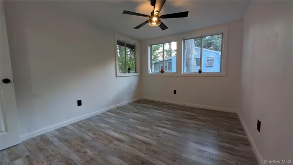 a view of an empty room with wooden floor and window
