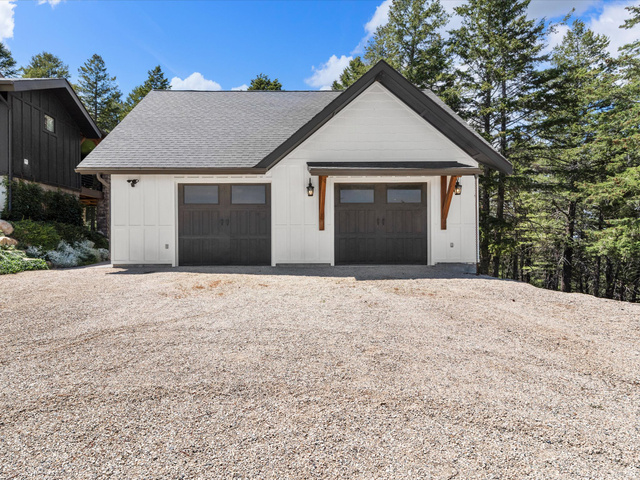 1225 Old Oregon Road Soda Springs, ID 83276 - Photo 57 of 67 Two-car garage featuring white vertical siding, dark gray doors with window panels, and a gabled roof