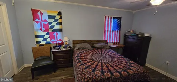 a bedroom with a bed and dresser with wooden floor