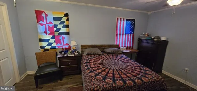 a bedroom with a bed and dresser with wooden floor