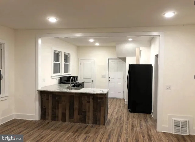 a kitchen with stainless steel appliances granite countertop a refrigerator a sink and wooden floors