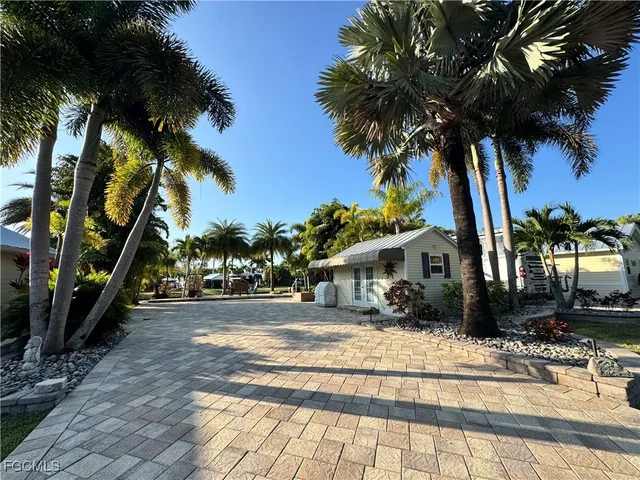 a view of a house with a yard and palm trees