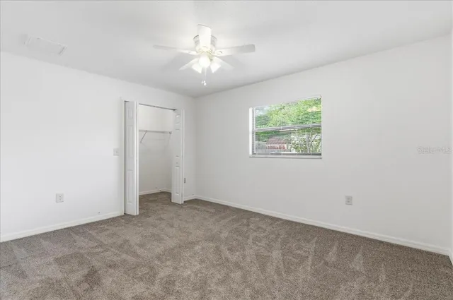 an empty room with windows and fan