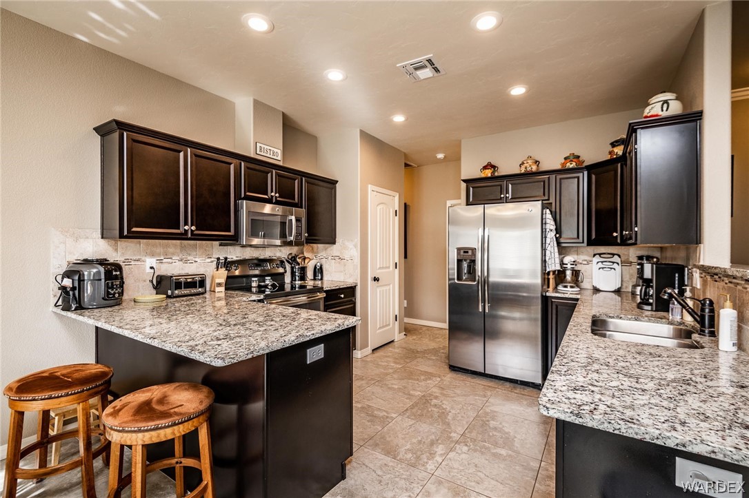 4870 North Old W Road Kingman, AZ 86401 - Photo 16 of 41 a kitchen with stainless steel appliances granite countertop a sink refrigerator and microwave