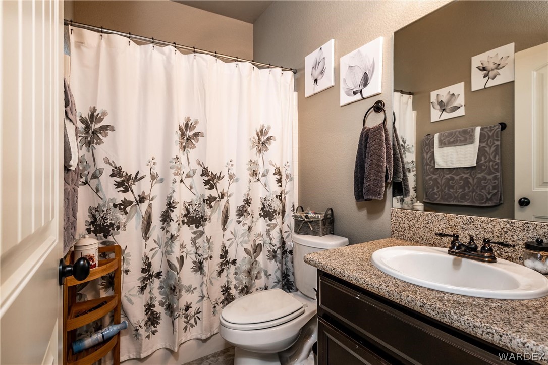 4870 North Old W Road Kingman, AZ 86401 - Photo 29 of 41 a bathroom with a granite countertop toilet sink and mirror