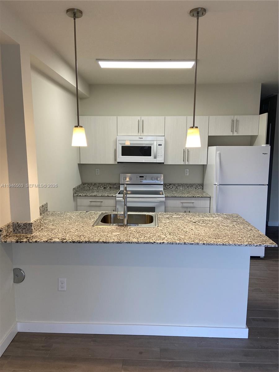 26511 Southwest 146th Court, Unit 117 Homestead, FL 33032 - Photo 3 of 6 a kitchen with kitchen island a counter top a sink and a stove