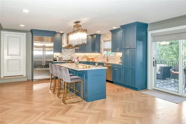 a kitchen with granite countertop a stove a refrigerator and a dining table with wooden floor