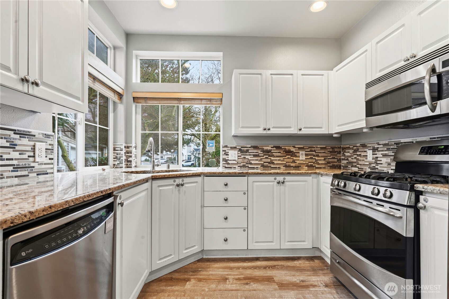 5624 South 233rd Street, Unit 41 Kent, WA 98032 - Photo 14 of 37 a kitchen with stainless steel appliances white cabinets and a stove a oven with wooden floor