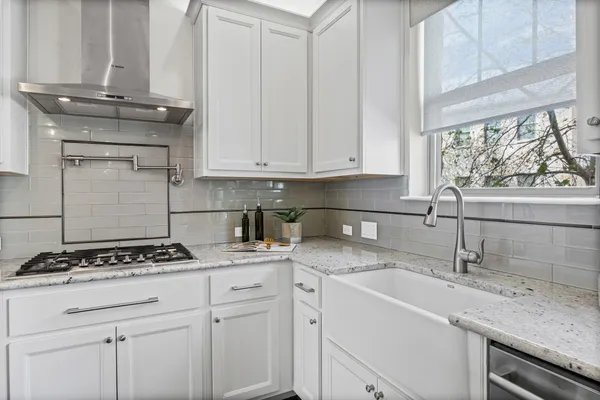 a kitchen with stainless steel appliances granite countertop a stove top oven a sink dishwasher a dining table and chairs with wooden floor