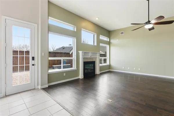 a view of an empty room with wooden floor fireplace and a window