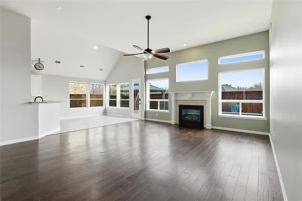 a view of empty room with wooden floor and kitchen